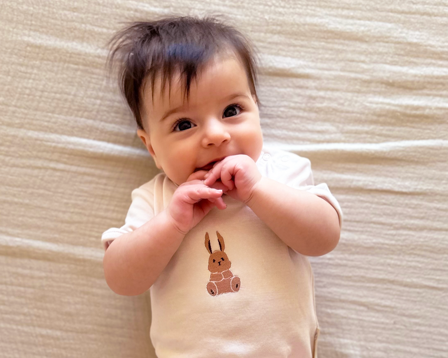 Baby wearing a pale pink onesie / bodysuit with a bunny design