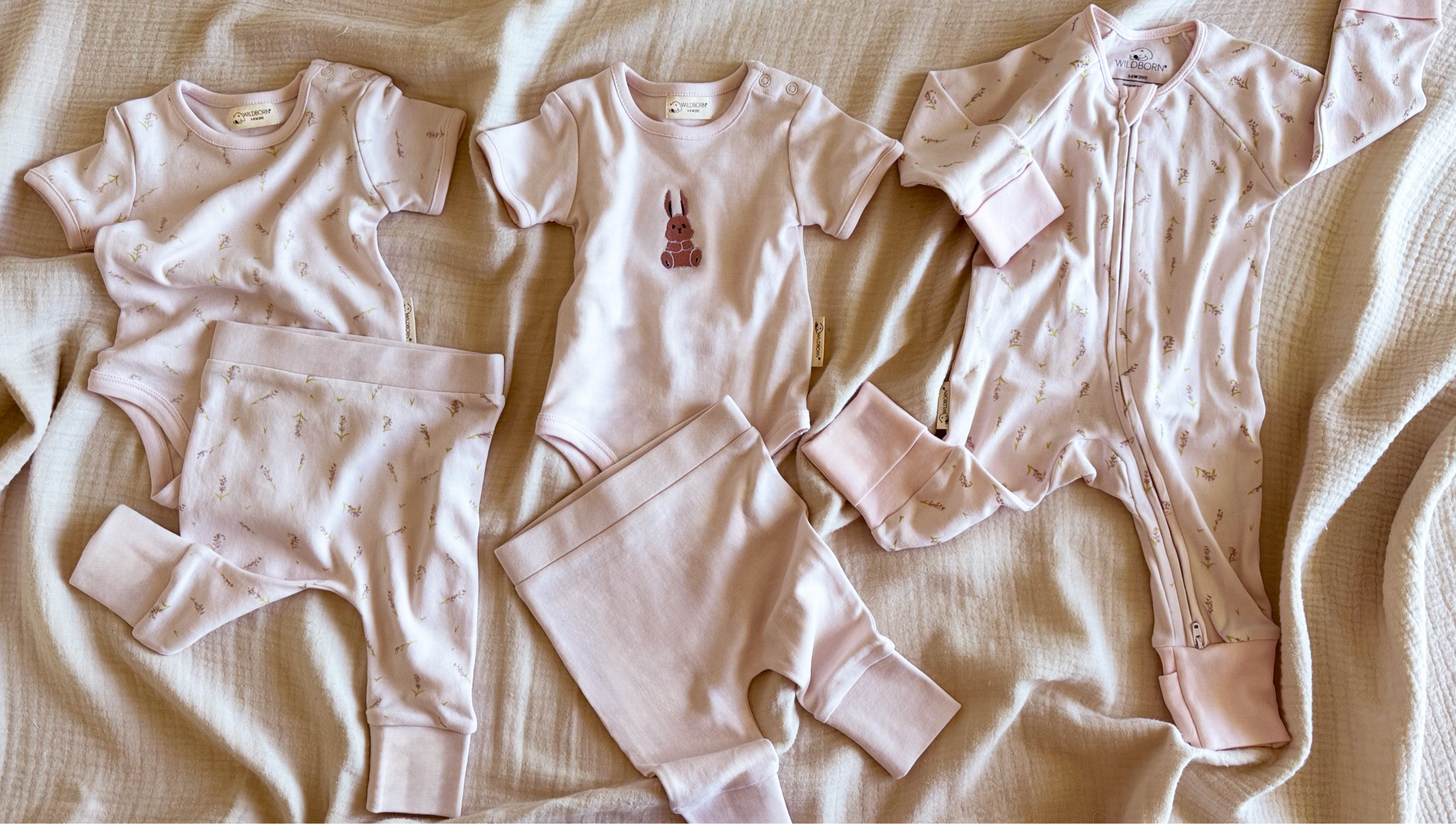 Collection of baby clothing items on a beige coloured surface
